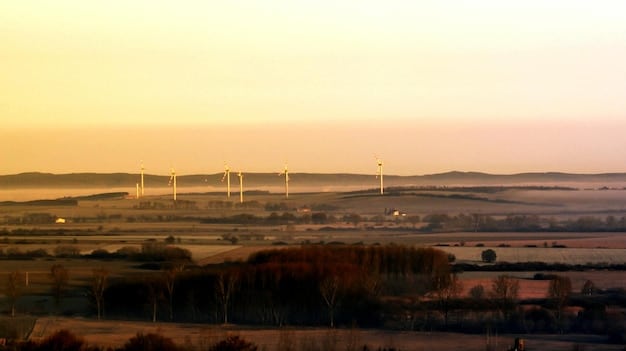 A wind farm at sunset with towering wind turbines, illustrating the shift towards renewable energy sources and the commitment to clean power.