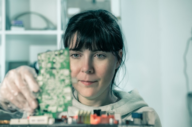 A female engineering student working on a complex circuit board in a university lab, with various high-tech equipment surrounding her. She is focused and determined, embodying the future of STEM.