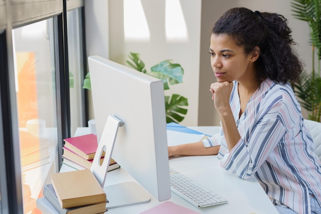 A student looking thoughtfully at a college application form on a desk, with a laptop displaying college websites in the background, emphasizing the decision-making process for test-optional admissions.