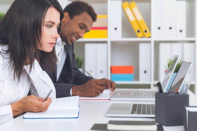 An admissions officer reviewing a student's application on a computer screen, with various documents and evaluation forms around them, illustrating the comprehensive and detailed process of college admissions. The scene is professional and focused.