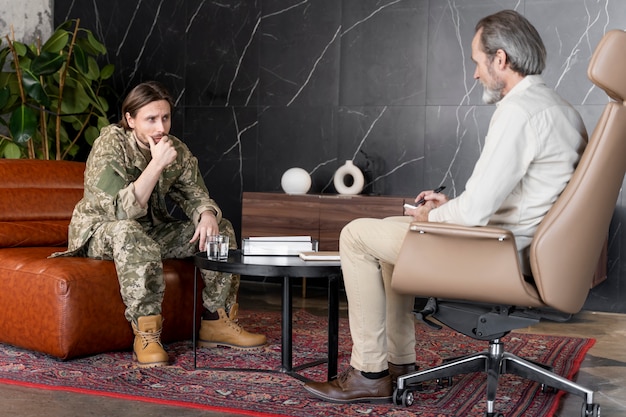 A veteran sitting at a desk, reviewing documents with a VA representative or counselor. The focus should be on the interaction, suggesting guidance and support.